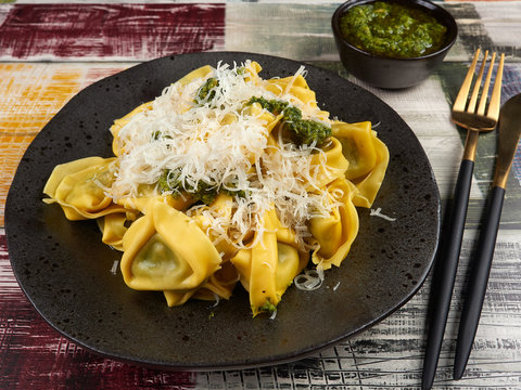 Fresh Italian traditional tortelloni with pesto sauce, on a rustic plate