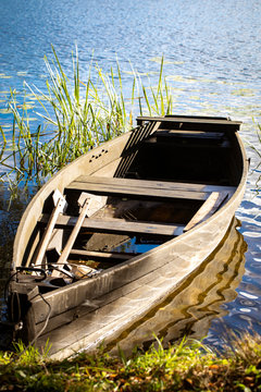 Masurian lake and a fishing boot. Colorful leaves, blue water and sunny skies with some white clouds. Masuria region, Poland.