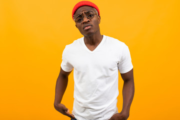 portrait of a stylish sexy african black man in a white t-shirt with glasses on a yellow background