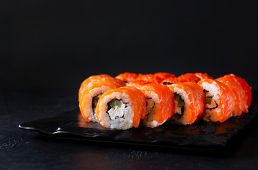 Philadelphia Japanese rolls with fresh salmon, soft cheese, cucumber and rice on a black background, Japanese sushi
