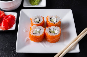 Philadelphia rolls with fresh salmon on a white plate, sticks, Japanese sushi, soy sauce , wasabi, ginger,