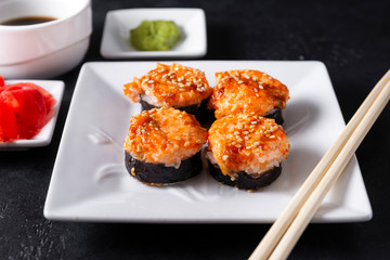 baked rolls with cream sauce caviar on a white plate, sticks, Japanese sushi, soy sauce , wasabi, ginger, sesame