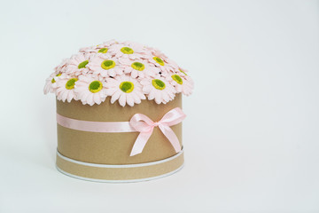 Flowers in bloom: a large bouquet of daisies in a round cardboard box.