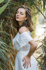 Portrait of a young beautiful girl in reeds in retro style in a light dress.