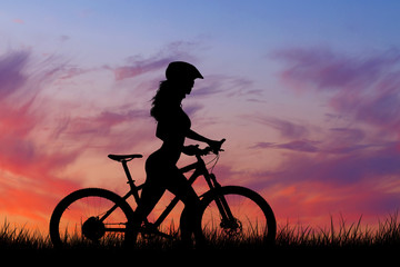Fototapeta premium Girl on a mountain bike on offroad, beautiful portrait of a cyclist at sunset, Fitness girl rides a modern carbon fiber mountain bike in sportswear, a helmet, glasses and gloves.