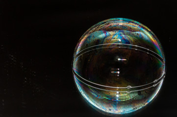 Colorful soap bubble on a black mirrored surface