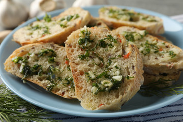 Plate with toasted garlic bread on towel, close up