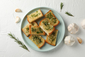 Plate with toasted garlic bread on white background, top view