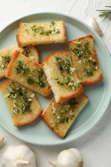 Plate with toasted garlic bread on white background, top view