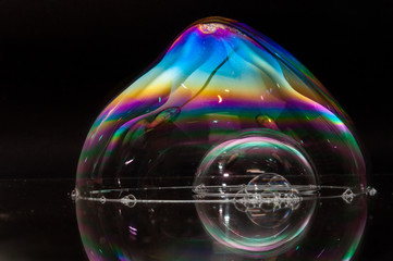 Colorful (rainbow) soap bubble on a black mirrored surface