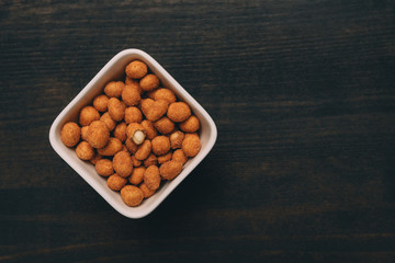 Salty peanut snack coated with barbecue sauce served on table