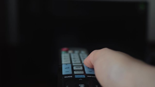Man's hand holding the remote control close-up and switches the TV channels. Secluded life.