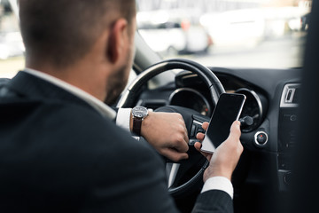 Handsome caucasian businessman driver inside in vehicle  with coffee and gadget and check mail and talking with partners