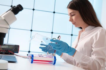 A young woman writes an algorithm for the robot arm. Science Research Laboratory for Robotic Arm...