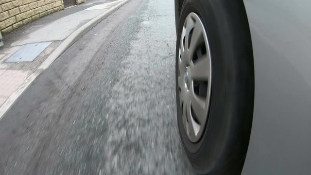 Vehicle tyre driving over a damaged road which is covered in Potholes in the street.  POV camera 