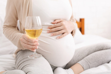 Pregnant woman holding glass of white wine