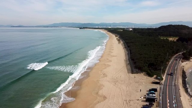 どこまでも続く砂浜に打ち寄せる波 空撮 トラックアップ 海の中道海岸_v142_00802_DJI_0010_1