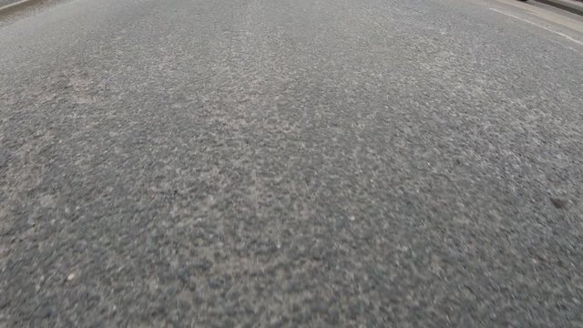 Vehicle driving over a bumpy, damaged road with covered in Potholes in the street.  POV