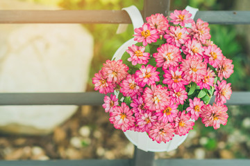 Beautiful artificial flowers in small pots hanging to decorate a railing walk for beauty on the pathway in public gardens. Selective focus.