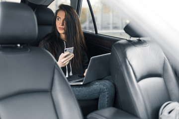Young pretty woman with smartphone and cup of coffee sit in car