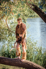 The Forest King. king of beasts in fur. wild young man. horns and makeup. fashion concept to chelowin. river forest and sun