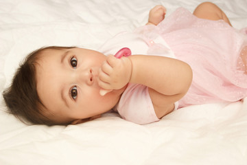 Little cute baby girl on the blanket with a heart shaped toy