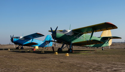 Old airplanes. Green and blue corncob. Sports plane of the 19th century. Until now they fly. Touch the antiquity. Propeller and wings. Airplane repair. Aerodrome. Blue sky. Sunny.