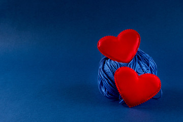 Blue knitting threads with red hearts on classic blue 2020 color background. Valentines day 14 february DIY concept. Copy space, top view, banner.