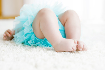 Close-up of legs and feet of baby girl on white background wearing turquoise tutu skirt. © Irina Schmidt