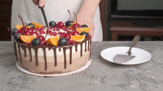 Slicing of three chocolate mousses decorated with berries, tangerine and pomegranate