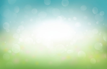A spring background of blue and green, blurred foilage and sky with bright bokeh.