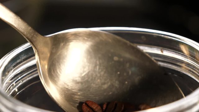Pouring coffee from a spoon. Coffee in the can. Coffee beans. Coffee. Black background. Close-up.