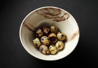 quail eggs in a deep clay bowl on a dark background