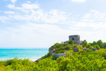 Fototapeta na wymiar Ruins of ancient Tulum. Architecture of ancient maya. View with sea. Blue sky and lush greenery of nature. travel photo. Wallpaper or background. Yucatan. Mexico.