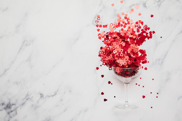 Champagne glass overflowing with red valentines heart confetti