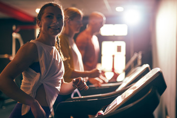 Group of people exercising in a gym cardio training and running