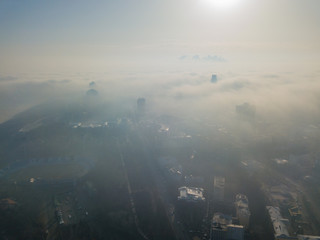 Aerial drone view. A foggy morning in Kiev, the silhouettes of houses are visible through the autumn fog.