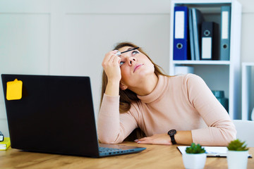 Pretty office girl applying mascara at workplace