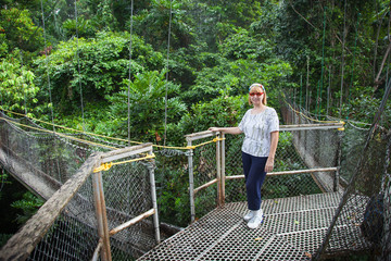 Suspended walkways at high altitude between trees in the Amazon jungle with a woman standing on a...