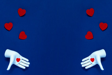 Two hands throw red hearts on a blue background. The concept for Valentine's Day