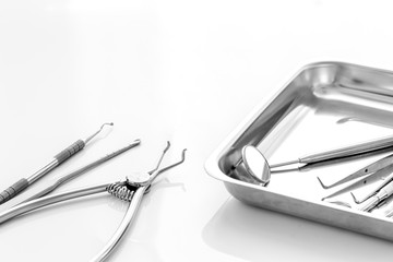 Dental instruments in stainless steel tray on white background close up copy space