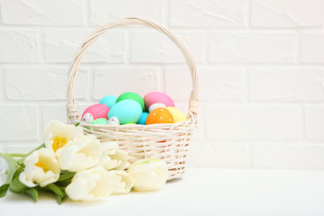 Easter eggs in a basket and flowers on the table. Festive easter background with place to insert text.