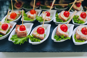 Buffet of different delicious food at a wedding celebration. Snacks for guests. Festive party. Canapes with tomato.