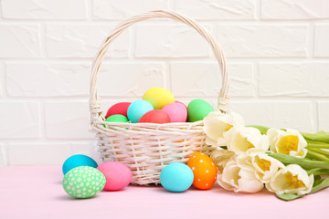 Easter eggs in a basket and flowers on the table. Festive easter background with place to insert text.