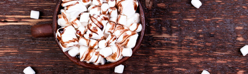 Banner of ot chocolate with marshmallow in brown cup on wooden background.