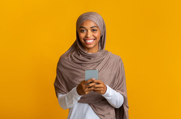 Cheerful Afro Muslim Girl In Hijab With Smartphone In Hands