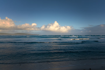 landscape of a Caribbean beach with white waves on the horizon blue sky and white clouds