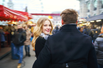 elegant romantic couple walking city street in a crowd of people. attractive blonde woman turn around and looking at camera.
