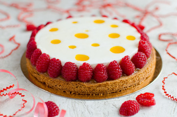 Contemporary exotic tart decorated with fresh raspberry on light background