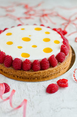 Contemporary exotic tart decorated with fresh raspberry on light background